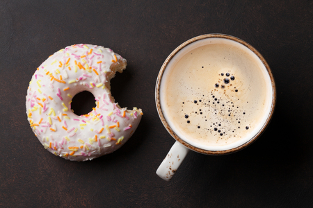 Coffee cup and donut on stone table. Top viewの写真素材