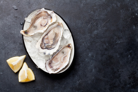 Opened oysters and lemon on stone table. Top above with copy spaceの写真素材