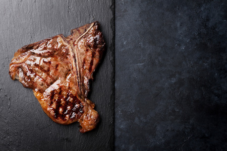 Grilled T-bone steak on stone table. Top view with copy spaceの写真素材
