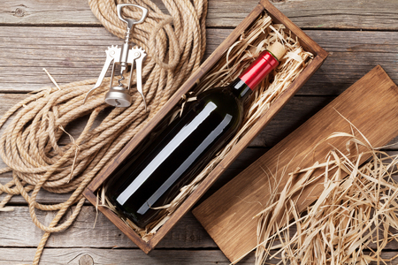 Red wine bottle in box on wooden table. Top viewの写真素材