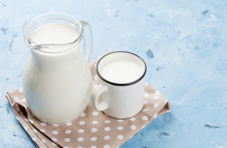 Milk jug and cup on stone table. Dairy productsの写真素材