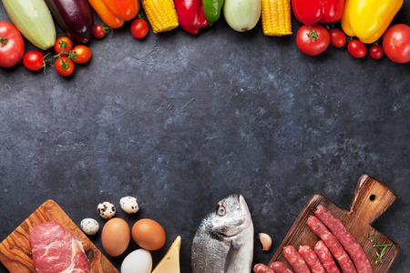 Vegetables, fish, meat and ingredients cooking. Tomatoes, eggplants, corn, beef, eggs, cheese. Top view with copy space on stone tableの写真素材