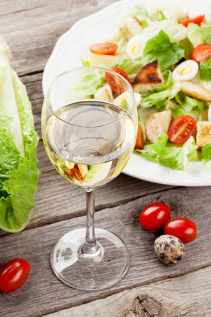 Fresh healthy salad and white wine on wooden tableの写真素材