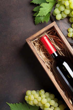 Red wine bottle in box and grapes on stone table. Top view with space for your textの写真素材