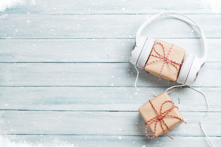 Christmas music gift concept. Headphones and gift boxes on wooden table. Top view with copy spaceの写真素材