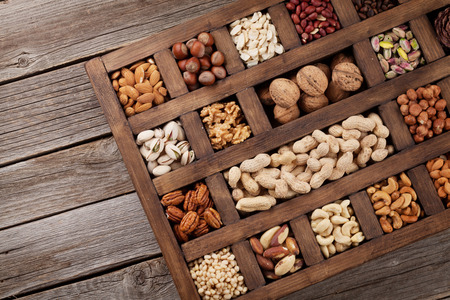 Various nuts selection: peanuts, hazelnuts, chestnuts, walnuts, pistachio and pecans in wooden box. Top view with space for your textの写真素材