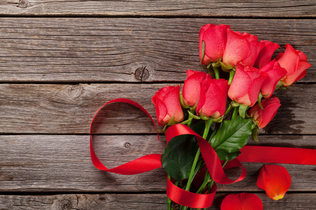 Valentines day greeting card with red roses on wooden background. Top view with space for your greetingの写真素材