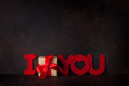 Valentines day greeting card with gift box and words over blackboard. With space for your greetingsの写真素材
