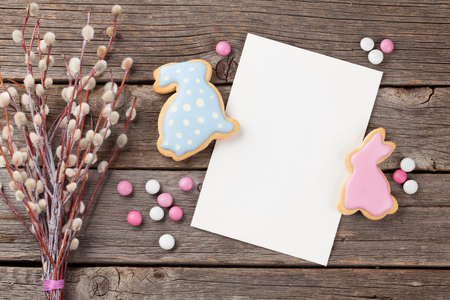 Easter gingerbread cookies and greeting card on wooden table. Colorful rabbits. Top view with space for your greetingsの写真素材