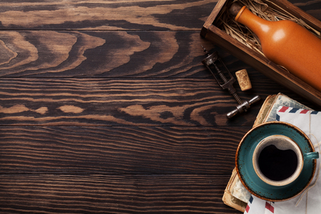 Retro table with vintage items. Coffee cup, books, envelope, wine bottle and corkscrew. Top view with space for your textの写真素材