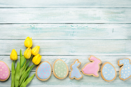 Easter gingerbread cookies and tulips on wooden table. Eggs and rabbits. Top view with space for your greetingsの写真素材