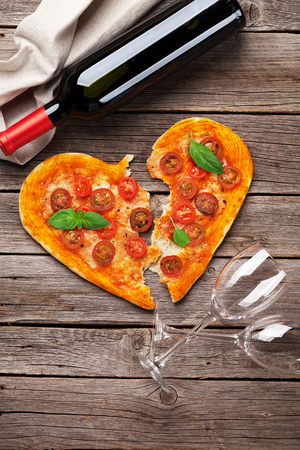 Heart shaped pizza with tomatoes and mozzarella and red wine bottle. Valentines day greeting card. Top viewの写真素材