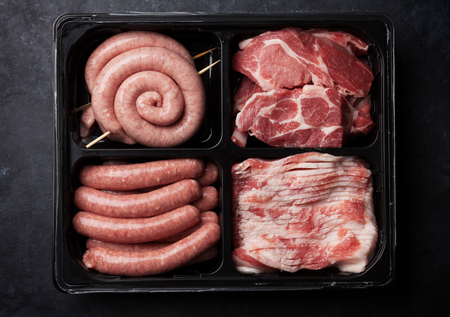 Raw meat and sausages in box. Top viewの写真素材