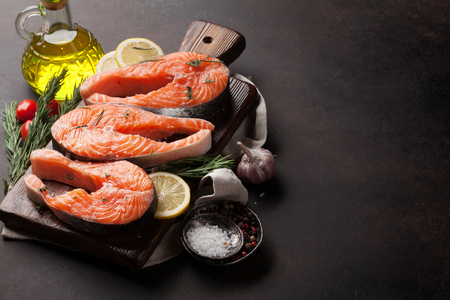 Raw salmon fish fillet with spices cooking on cutting board. With space for your textの写真素材