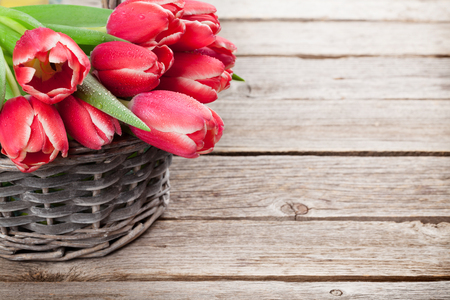 Red tulip flowers bouquet on wooden background. Easter or Valentine's day greeting card. With space for your greetingsの写真素材