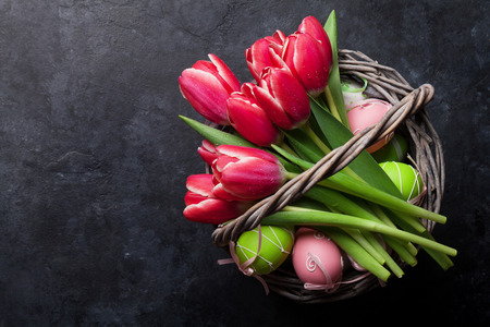 Red tulip flowers bouquet and easter eggs. Easter greeting card. Top view with space for your greetings on blackboardの写真素材