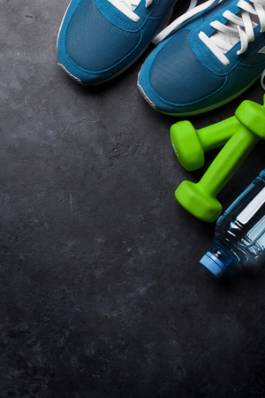 Fitness concept background with sneakers, dumbbells and water bottle. Top view with space for your textの写真素材
