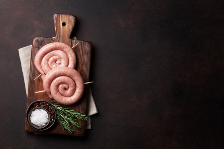 Raw sausages cooking on wooden cutting board. Top view with space for your textの写真素材
