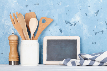 Kitchen utensils in front of stone wall and blank chalkboard for your textの写真素材