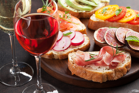 Brushetta or traditional spanish tapas. Appetizers italian antipasti snacks set on wooden board with rose and white wineの写真素材