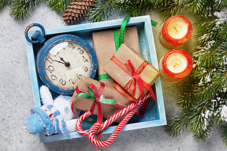 Christmas decor box, gift boxes, candles and fir tree branch on stone background. Top view