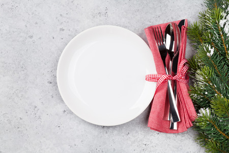 Christmas table setting with empty plate, silverware and fir tree branch on stone background. Top view with space for your greetingsの写真素材