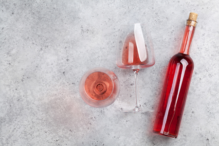 Rose wine bottle and glass lying on stone backdrop. Top view with space for your textの写真素材