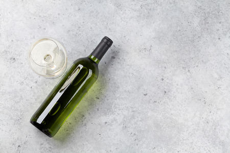 White wine bottle and glass lying on stone backdrop. Top view with space for your textの写真素材