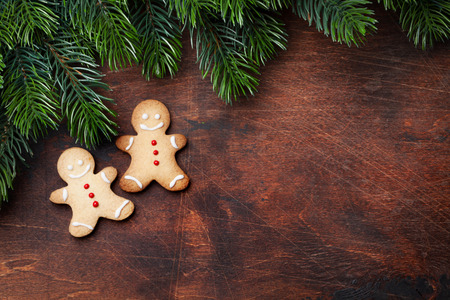 Christmas gingerbread cookies and xmas fir tree branch over wooden backdrop. Top view with space for...