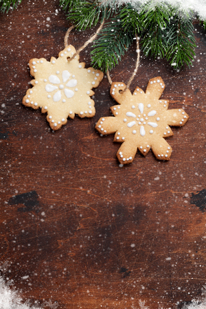 Christmas gingerbread cookies and xmas fir tree branch over wooden backdrop. Top view with space for your greetingsの写真素材