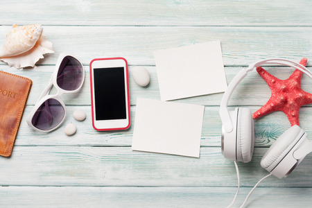 Travel vacation and music concept with headphones, sunglasses, smartphone, seashells and photo frames on sand backdrop. Top view with copy space. Flat layの写真素材