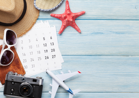 Travel vacation background concept with sunglasses, hat, camera, passport, airplane toy and calendar on wooden backdrop. Top view with copy space. Flat layの写真素材