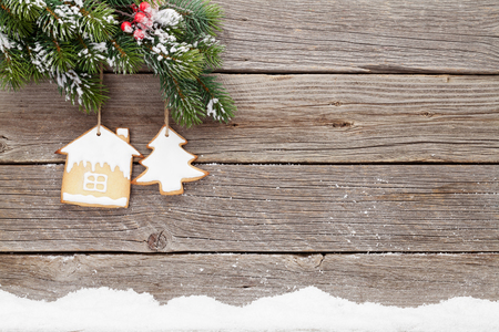 Christmas card with gingerbread cookies and fir tree branch covered by snow in front of wooden wall. With space for your greetingsの写真素材