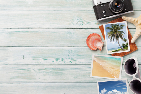 Travel vacation background concept with sunglasses, camera and weekend photos on wooden backdrop. Top view with copy space. Flat lay.の写真素材