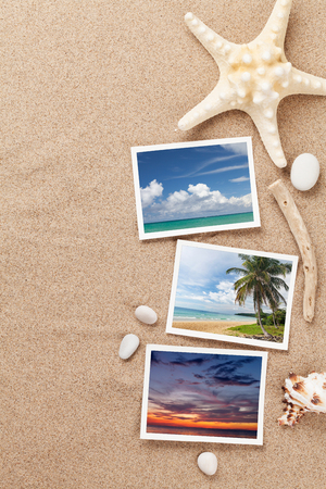 Travel vacation background concept with seashells and photos on sand backdrop. Top view with copy space.の写真素材