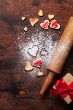 Valentine's day greeting card with cooking heart shaped cookies on wooden background. Top view with space for your greetings. Flat layの写真素材
