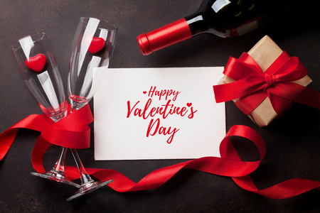 Valentine's day greeting card with red wine bottle and love gift box on stone background. Top view with space for your greetings. Flat layの写真素材