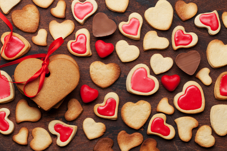 Valentine's day greeting card with heart shaped cookies and sweets on wooden background. Top view. Flat layの写真素材