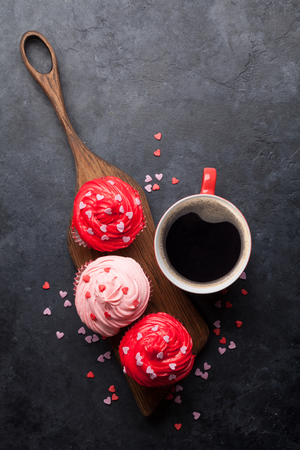 Valentine's day greeting card with delicious sweet cupcakes and coffee cup on stone background. Top view with space for your greetingsの写真素材