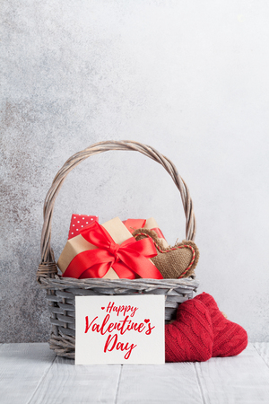 Valentine's day greeting card with gift boxes and knitted hearts in basket. With space for your greetingsの写真素材