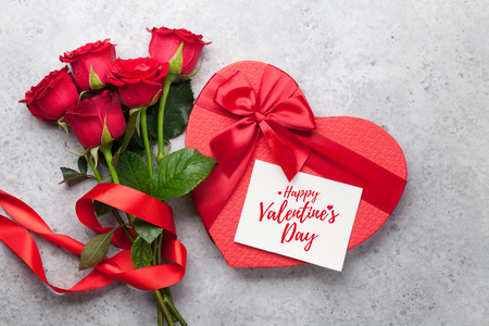 Valentine's day greeting card with red rose flowers bouquet and gift box on stone background. Top viewの写真素材
