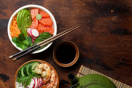 Poke bowl with salmon, shrimps and vegetables. Traditional Hawaiian raw fish salad. Top view with copy spaceの写真素材