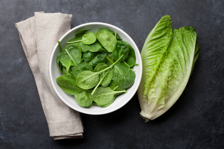Romaine lettuce and spinach salad on stone table. Top viewの写真素材