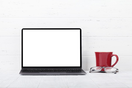 Loft home office workplace with blank white screen laptop computer and coffee cup. With copy space for your mockup or textの写真素材