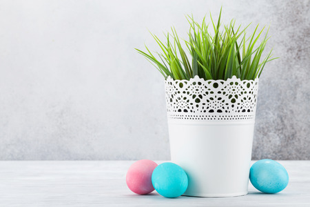 Easter greeting card with grass and colorful easter eggs. In front of stone wall with space for your...