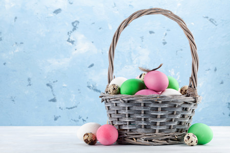 Easter greeting card with colorful easter eggs in basket. In front of stone wall with space for your...