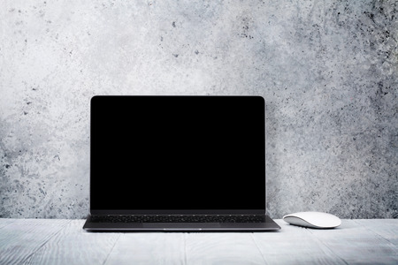 Loft home office workplace with blank black screen laptop computer. With copy space for your mockup or textの写真素材