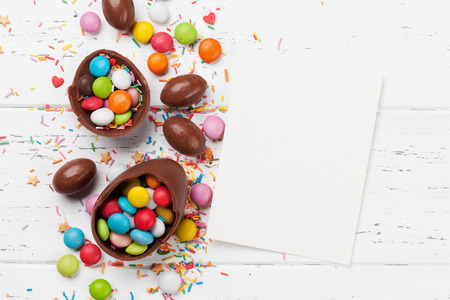Easter greeting card with chocolate eggs and candies. Top view on wooden table with space for your...