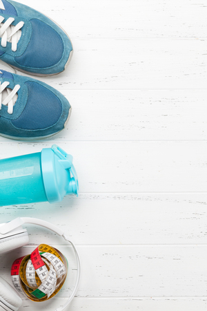 Fitness concept. Sneakers, headphones and drink bottle on woodenの写真素材