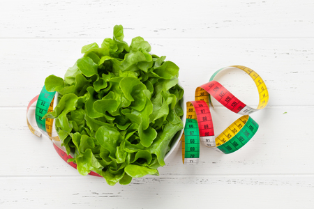 Healthy food concept. Fresh salad and tape measure. Top view flat lay with copy space for your textの写真素材